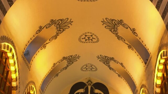 Slow tilt up shot capturing the ornate vaulted ceiling and intricate traditional Ottoman motifs of a historic indoor marketplace in Istanbul, Turkey.