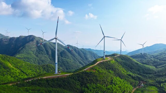 Wind turbines stand on green mountain ridges against blue sky with white clouds, generating clean renewable energy for sustainable development.