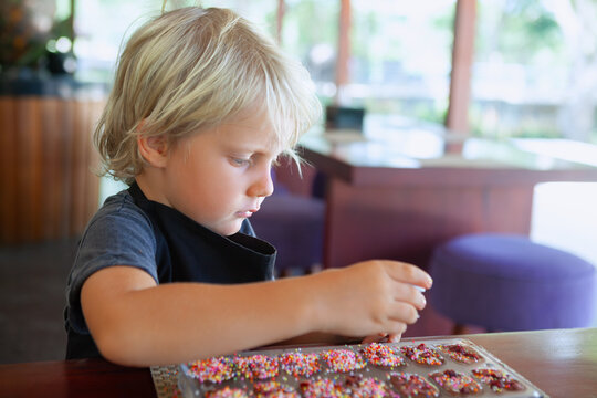 Young boy selects colorful toppings for handmade chocolates during a creative family workshop on summer family holidays inBali . A fun and tasty travel experience for children.