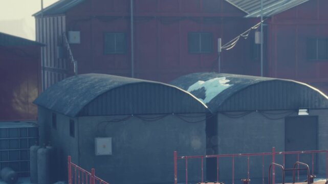 Two buildings are shown with a basic design and storage space in a rural setting. The scene captures structures in a simple setting where functionality is the focus.