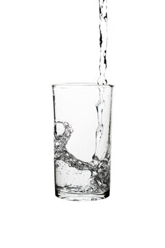 Fresh water pouring into a clear drinking glass isolated on a white background.