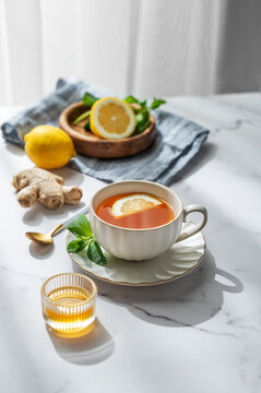 Cup of tea with lemon, ginger and mint on a marble background with honey