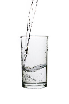Pouring fresh drinking water into a clear glass isolated on a white background. Hydration, purity, refreshment, and healthy lifestyle concept.