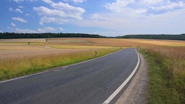 Einsame Landstra&szlig;e durch eine goldene Landschaft mit Getreidefeldern unter klarem Himmel, Beuerbach, H&uuml;nstetten, Taunus, Rheingau-Taunus-Kreis, Hessen, Deutschland