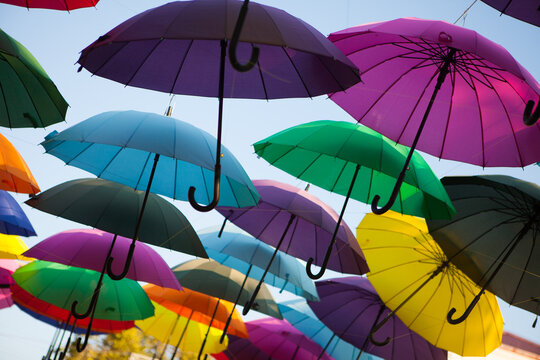 Multicolored umbrellas creating a decorative canopy in the open air, vibrant outdoor display, creative background, summer festival.