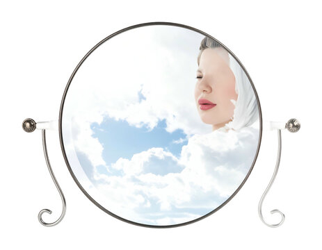 Surreal composite of a woman appearing within the clouds reflected in a mirror