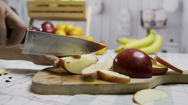 Closeup shot of woman's hands using knife to slice up delicious looking red apple on cutting board