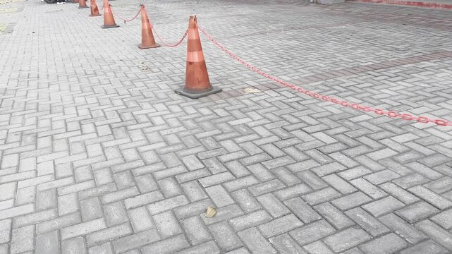 Orange Traffic Cones with Warning Rope on Paving Sidewalk