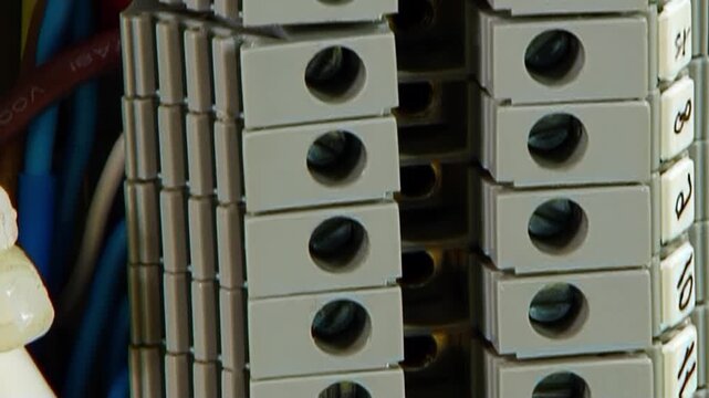 Observe the detailed process of electrical wiring. Various colored cables attach securely to gray terminal blocks and a shining brass ground bar.