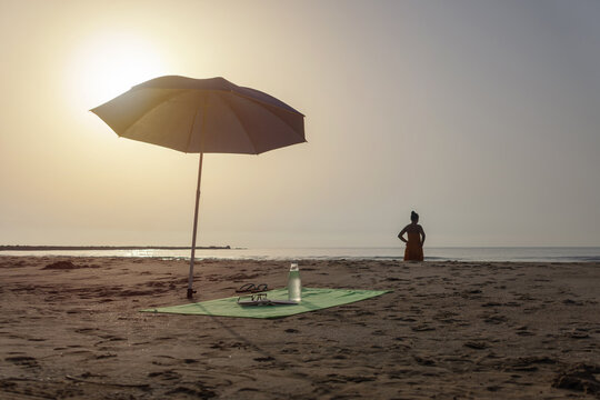 Beach umbrella with towel book and water bottle by the sea