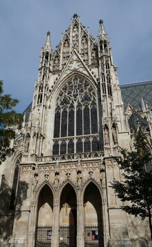 Low angle view of the magnificent Votivkirche cathedral in Vienna, highlighting the historic Neo-Gothic stone carvings, high arches, windows, and decorative spires.