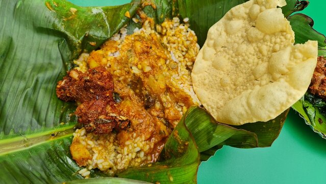 Traditional Kerala Pothichoru Served on Banana Leaf with Rice Curry Fried Side Dish and Pappadam