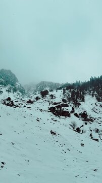 4K vertical view of snowfall in mountains during winter season at Chandanwari, Jammu and Kashmir, India. Winter background. Snow covered Himalayas and stormy clouds in sky. Nature landscape.