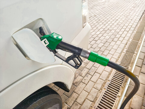 Driver refueling white car with gasoline fuel nozzle at gas station. Automotive energy service, petrol pump, vehicle maintenance and transport transportation industry concept