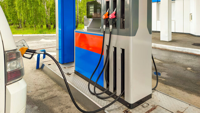 Gas station pump filling white vehicle with fuel. Petrol dispenser at station. Modern energy service station for automobile refueling. Concept of transport logistics and fuel supply