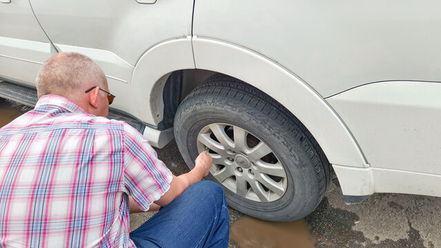Man inflating vehicle tire at gas station. Driver tightening valve cap after using air compressor to maintain car wheel pressure. Automotive maintenance and road safety service concept