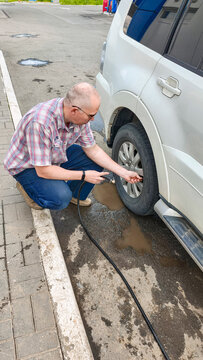 Man inflating car tire with air compressor at gas station. Driver checking vehicle wheel pressure. Maintenance service for automobile travel safety. Automotive transport care concept