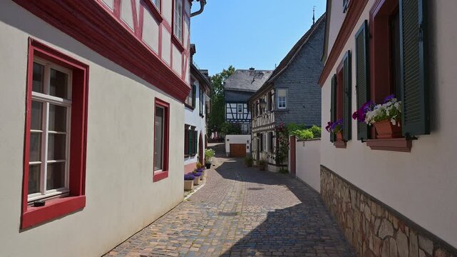 Malerische Gasse mit Fachwerkarchitektur und Kopfsteinpflaster unter klarem blauem Himmel, Bachgasse, Eltville am Rhein, Rheingau, Hessen, Deutschland 