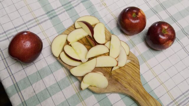 High shot of man's handing taking red apple slices on wooden cutting board