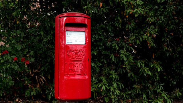 Leicester, England, UK - 26 July 2026: British red post box, Royal Mail pillar box with Elizabeth II Cypher against green foliage