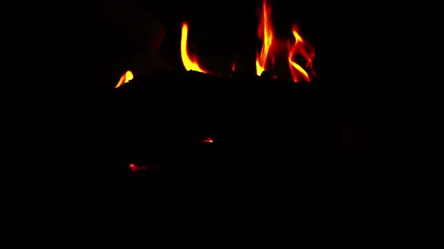 Close-up of burning firewood inside a wood-burning stove with glowing flames creating a warm and cozy atmosphere