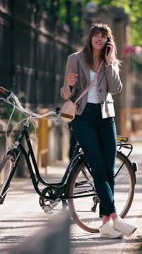 Video of beautiful woman talking on the phone while riding a bicycle through the park