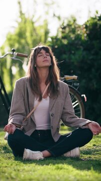 Video of pretty woman doing ioga while resting after cycling in the park.