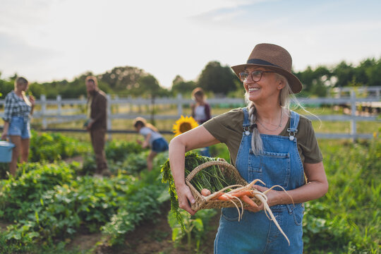 Happy farmers or gardeners working outdoors at community farm.