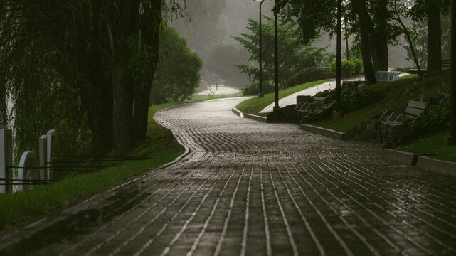 Heavy rain falls on an empty riverside park path