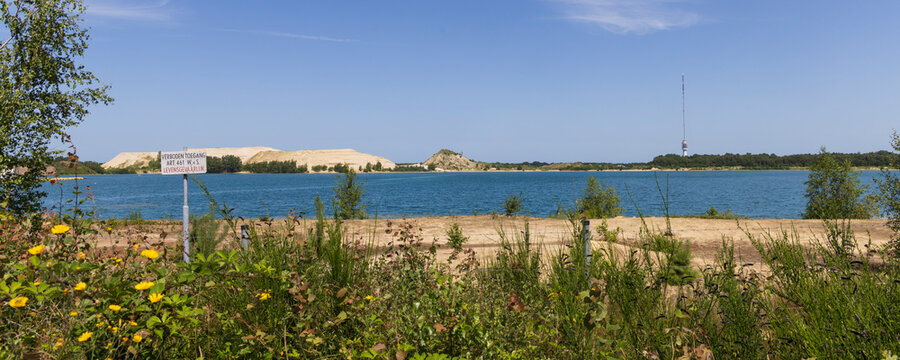 Lake Achterste Plas for sand extraction in Hoogersmilde in Drenthe,  Netherlands with danger sign,  blue water and sandy shore