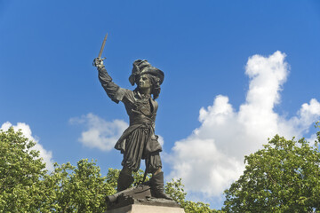 Obraz premium The Jean Bart statue rises above its pedestal in Dunkirk, the naval hero lifting his sword toward the clear sky.