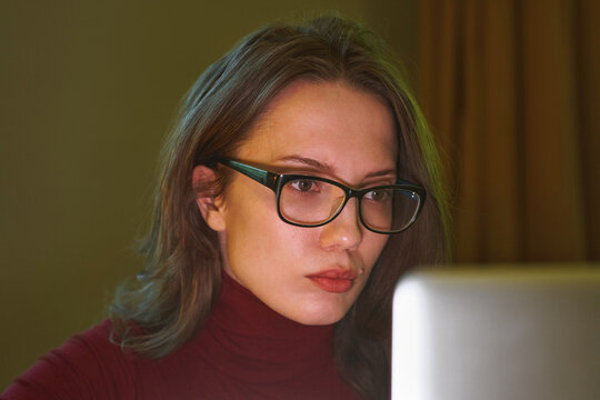 Focused woman with eyeglasses working late on laptop