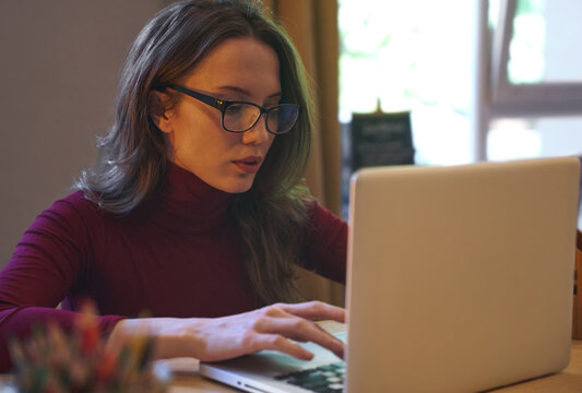 Focused businesswoman overworking on laptop with eyeglasses
