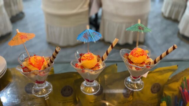 Three Falooda Desserts in Glass Bowls Decorated with Paper Umbrellas and Wafer Sticks - Video Footage