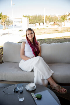 Woman relaxing on cafe sofa with coffee during remote work