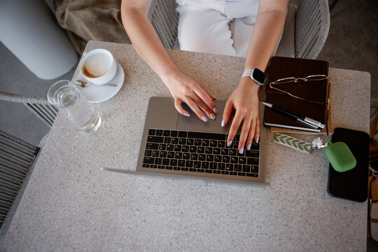 Top view of remote worker typing on laptop at cafe table