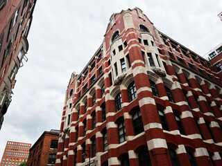 Obraz premium Historic red brick architecture and ornate commercial building in Manchester, UK captured from dramatic low angle perspective