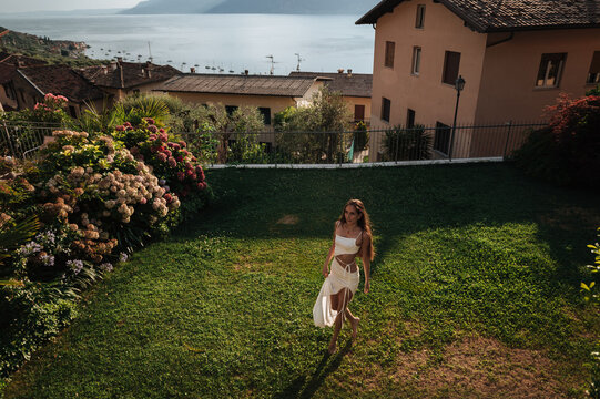 Young woman in white dress in garden with lake city view