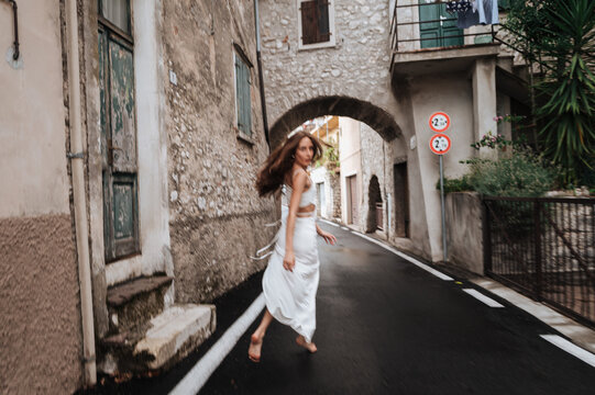 Young woman walking through old street arch in Garda, Italy
