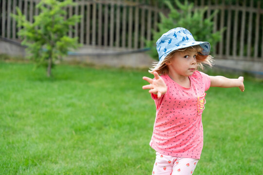 Little Girl Reaching Forward While Running In Garden During Summer Outdoor Play
