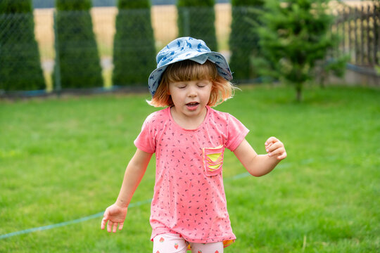 Little Girl Walking In Garden Wearing Sun Hat During Happy Summer Childhood