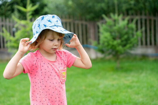 Little Girl Adjusting Sun Hat In Garden During Summer Outdoor Childhood Lifestyle