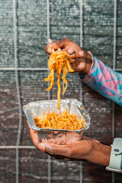 Gen Z woman eating takeaway noodles from foil container
