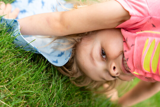 Happy Little Girl Doing Bridge Stretch On Grass During Outdoor Fitness And Summer Play