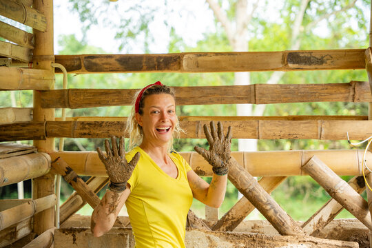 Woman showing muddy hands during natural house construction