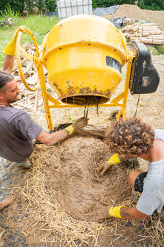Workers mixing clay and straw for natural house construction