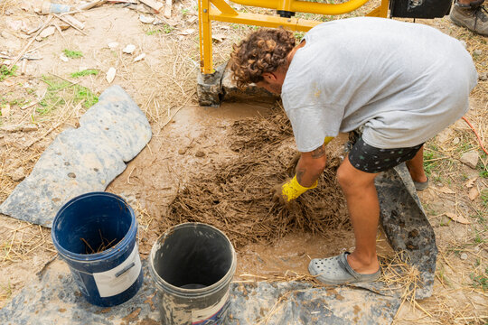 Worker mixing straw into clay for natural house construction