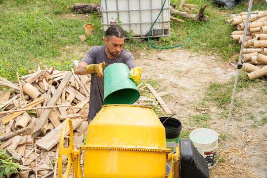 Worker adding water to concrete mixer for clay mixture