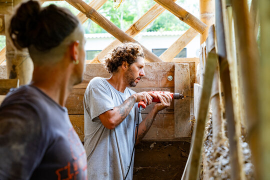 Worker drilling timber frame during eco construction