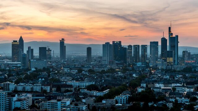Day to night timelapse of the Frankfurt skyline featuring the modern financial district and illuminated skyscrapers as the city transitions from sunset to blue hour.